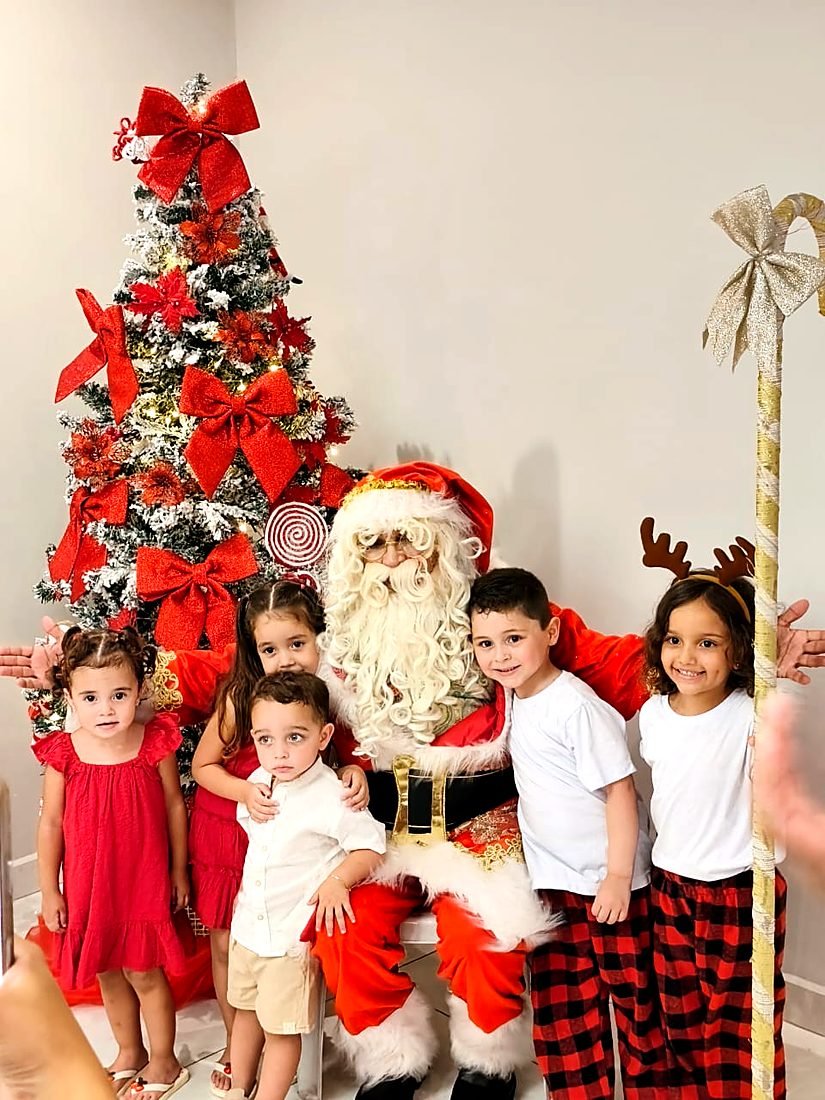 Papai Noel com crianças ao lado da árvore de Natal